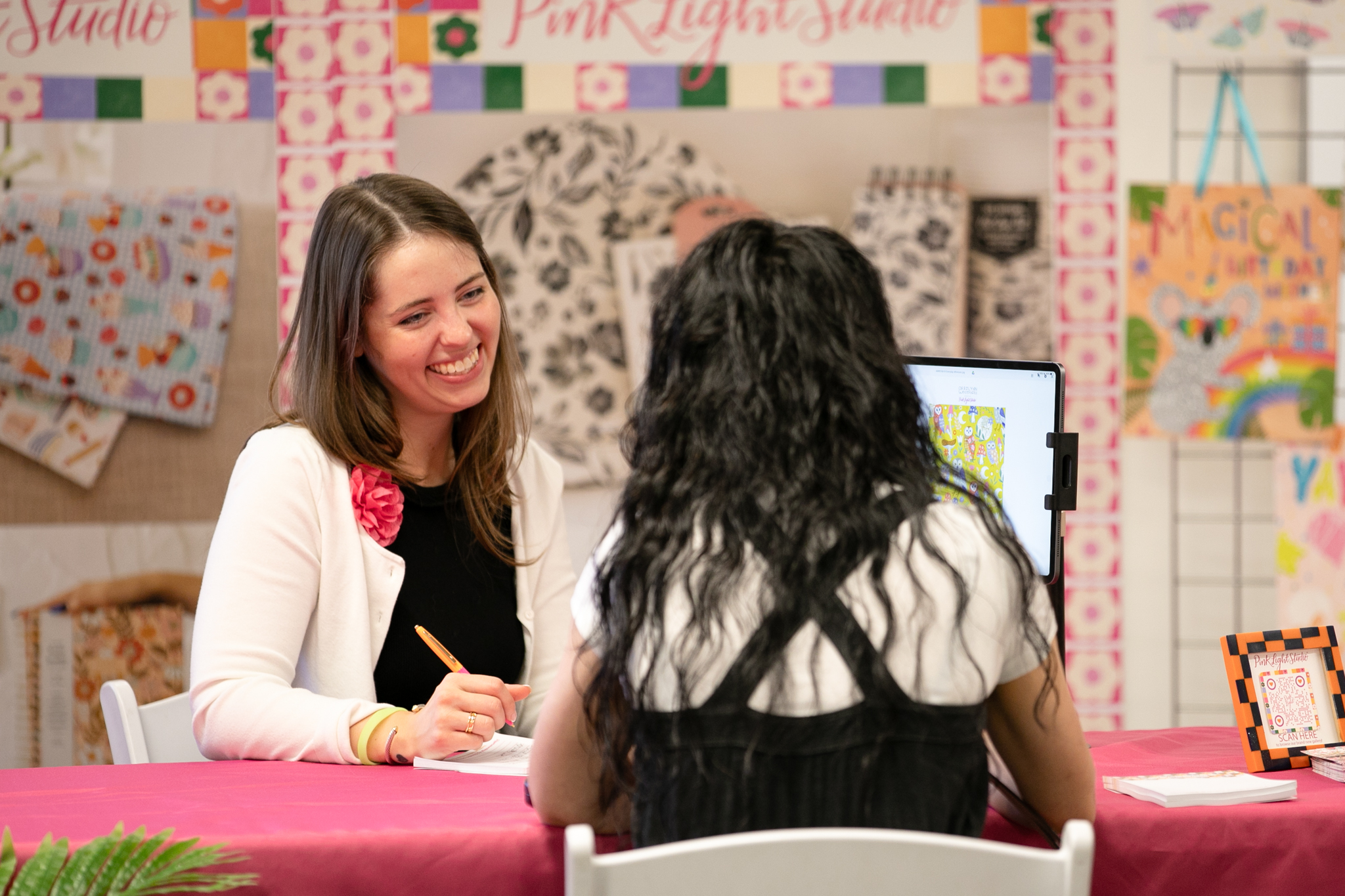 Smiling exhibitor discussing design prints with an attendee at Printsource trade show.