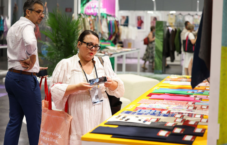 Attendees browsing colorful fabric samples at a booth during Texworld Los Angeles