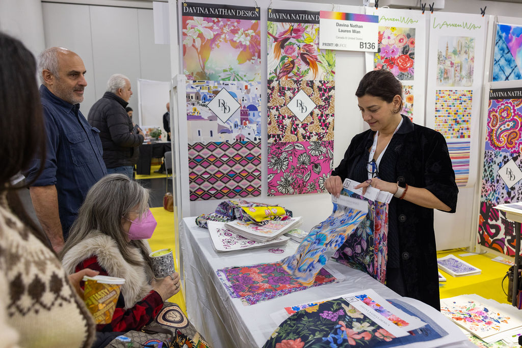 Exhibitor displaying vibrant printed textiles to attendees at Texworld Los Angeles.